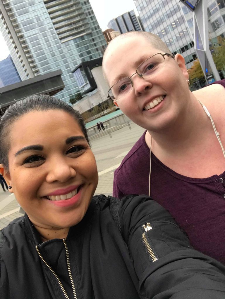 Selfie of instructors Harmony and Heather. Behind them are buildings.