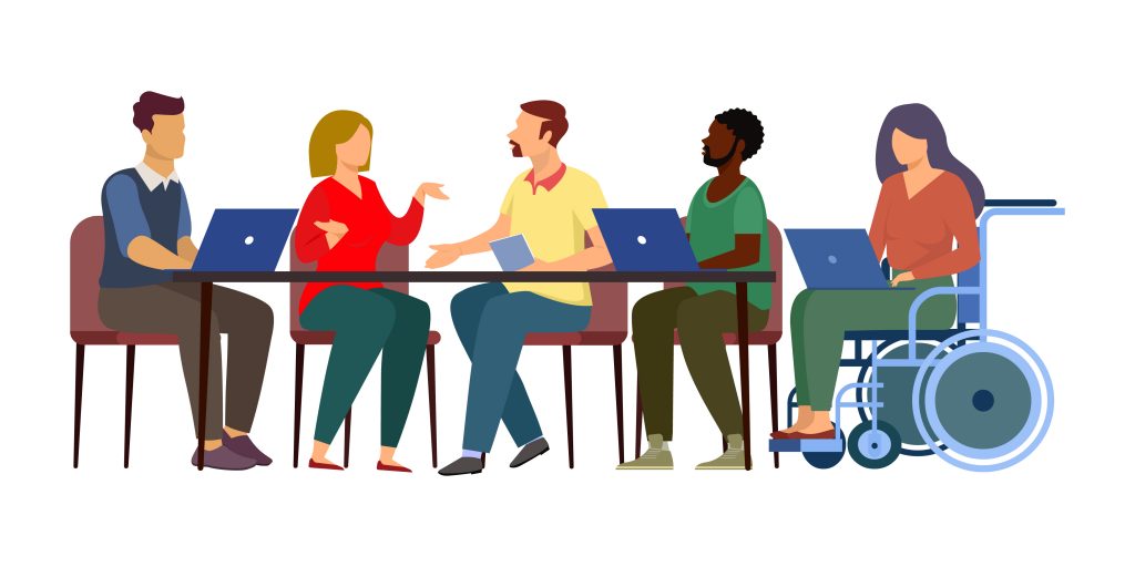 5 diverse people at work, siting at table talking, 2 have computers on the table, 1 has a computer on their lap.